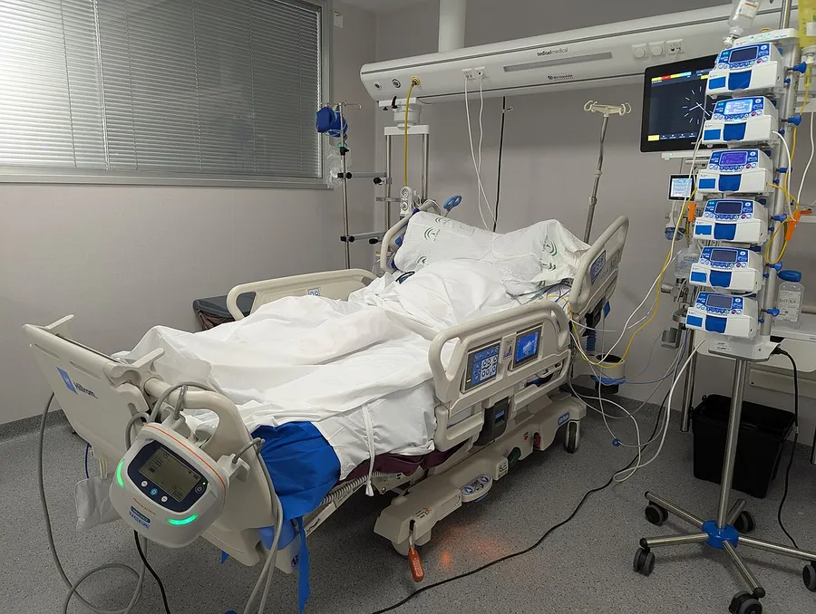 Intensive care bed with monitors and infusion pumps on an IV pole