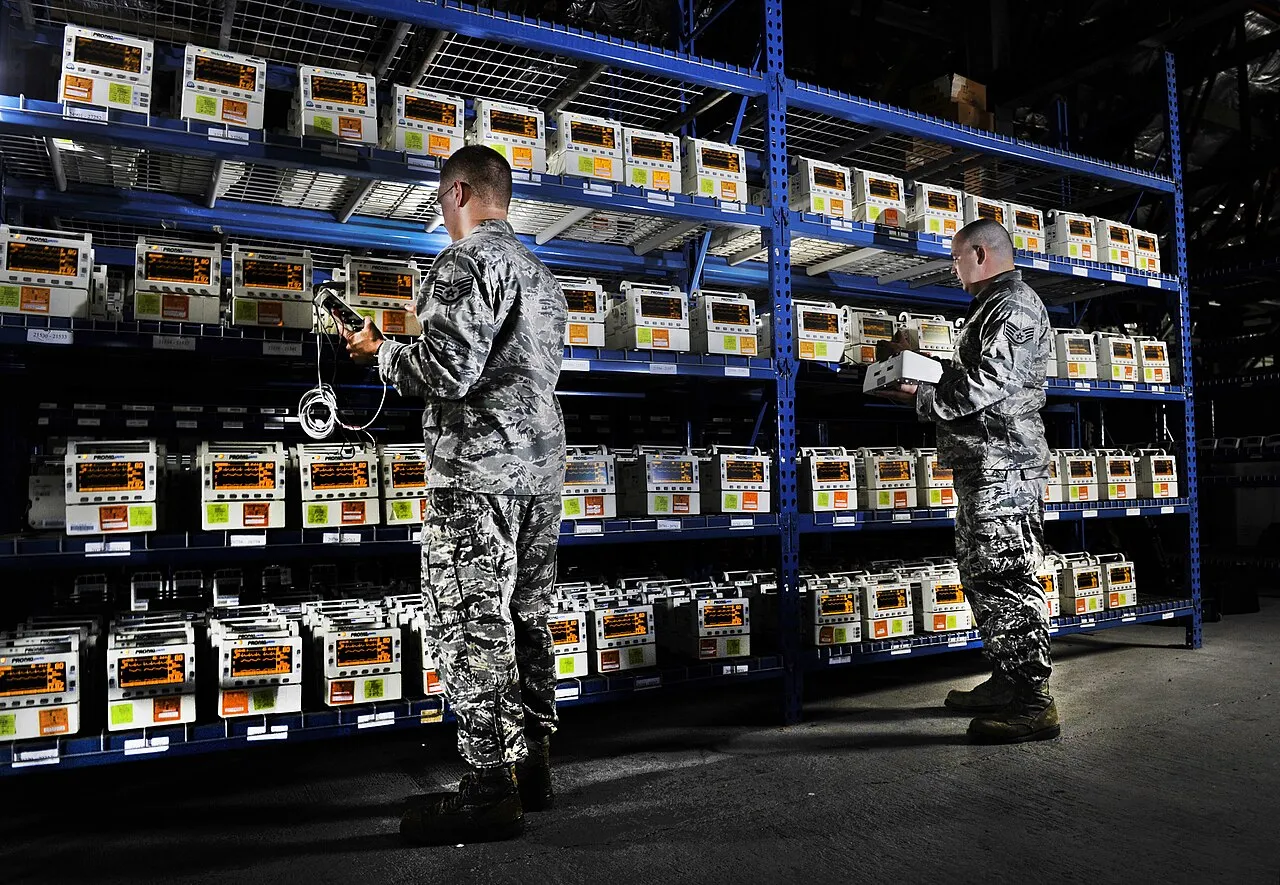 Biomedical technicians checking shelves of infusion pumps in an equipment room